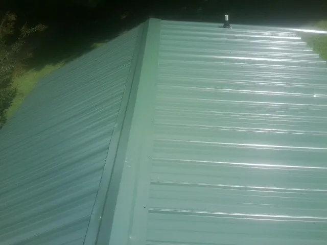 New green metal panels meeting at the ridge of a roof — Flat Roof Repair work by our crew in Bozrah