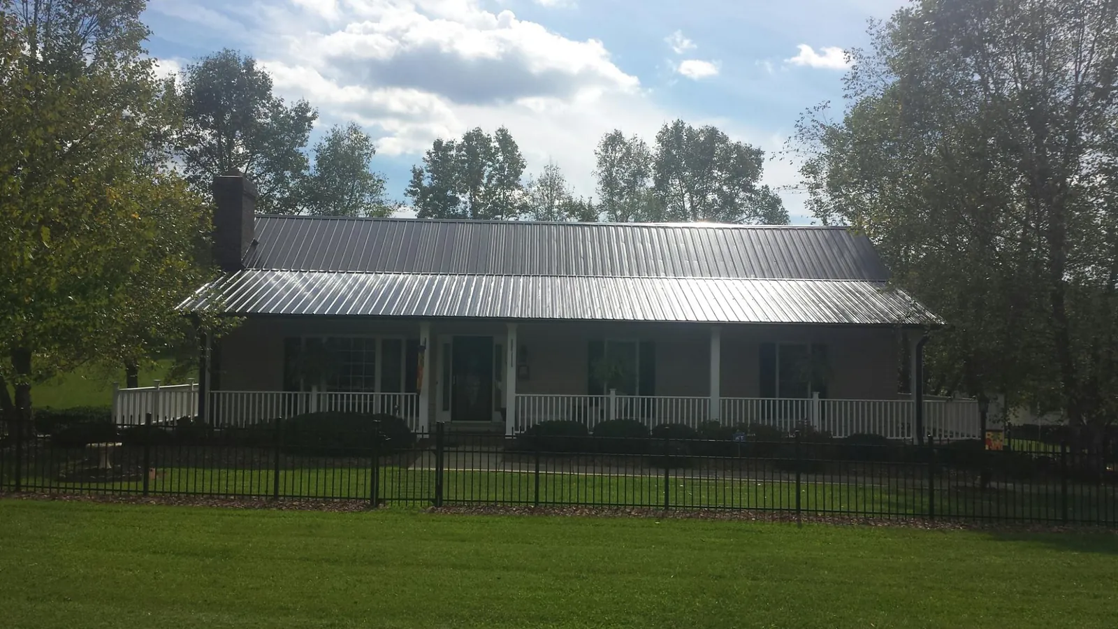 Gray metal roof on a brick ranch with a full width front porch — Gutter Guard Installation work by our crew in Bozrah