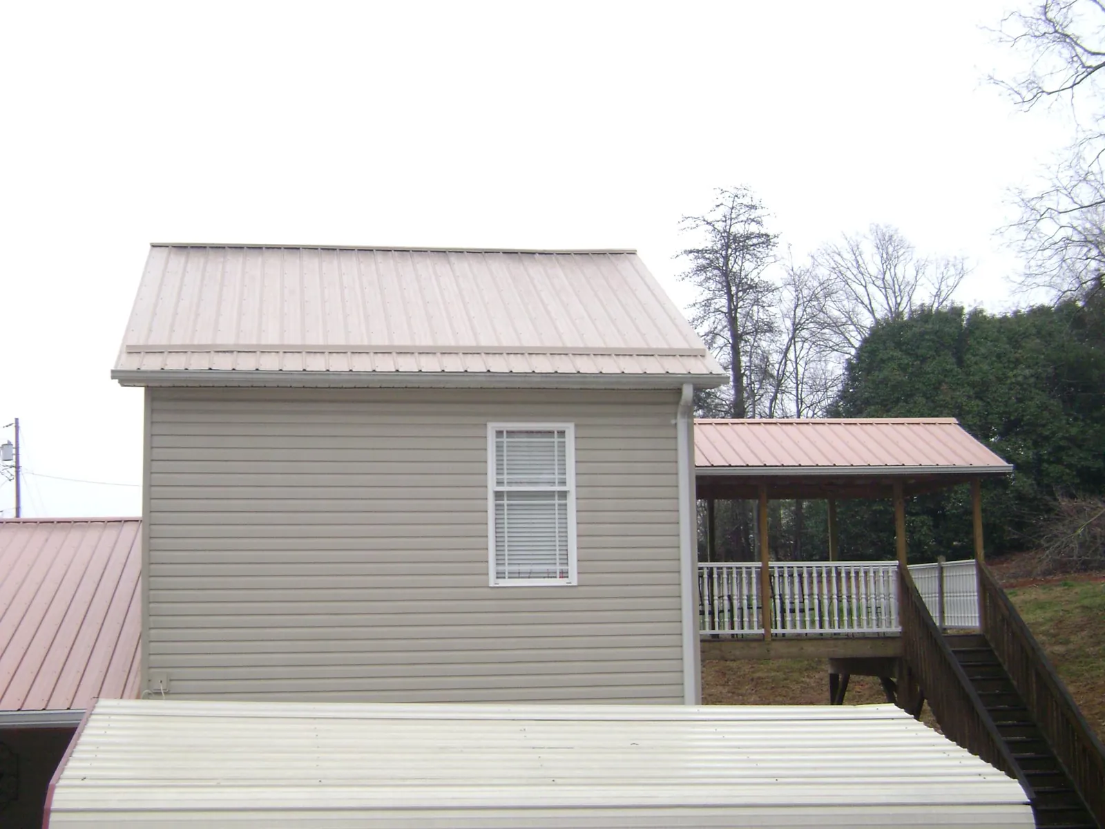 Tan metal roofs on a two story addition and attached porch, from a Roof Replacement job in Bozrah
