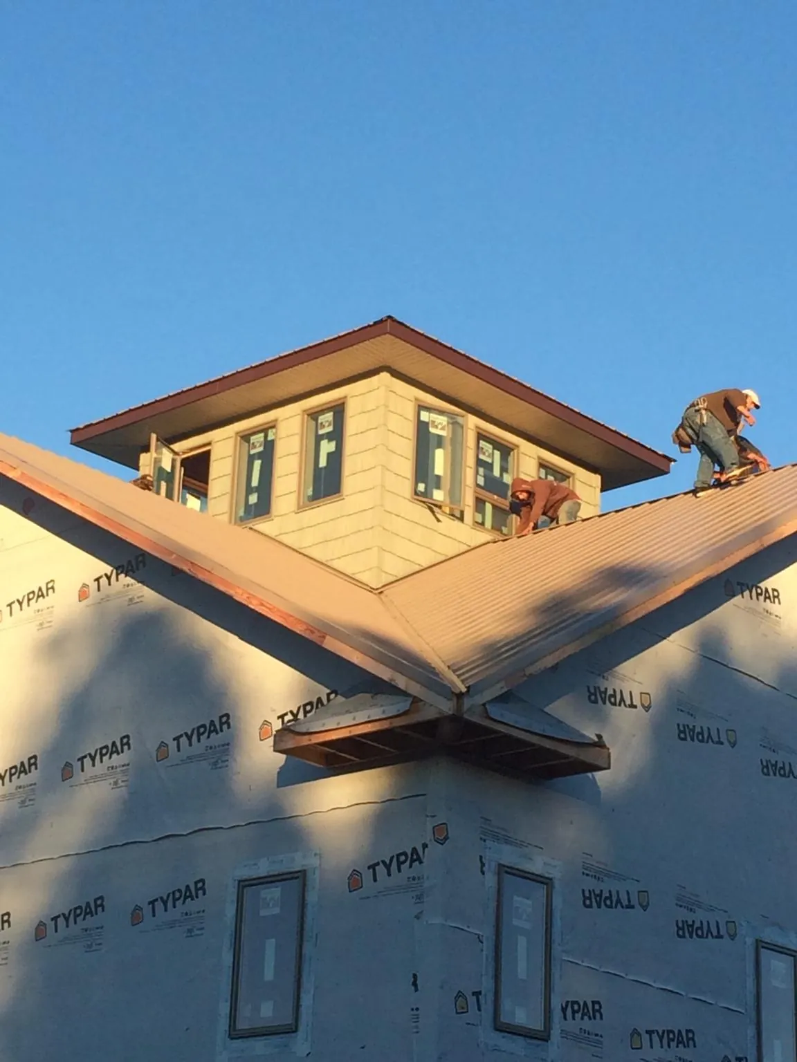 Roofers working around a rooftop cupola on a new metal roof at sunset — Roof Waterproofing in Bozrah by Roofing Brothers